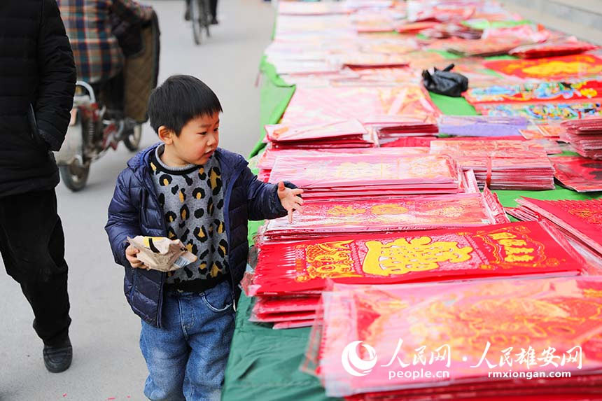 雄安街頭開始陸陸續(xù)續(xù)出現(xiàn)售賣春聯(lián)的攤位。火紅的春聯(lián)吸引著人們紛紛駐足挑選,圖為小朋友在家長的陪同下挑選著面前的春聯(lián)。 張慕天攝