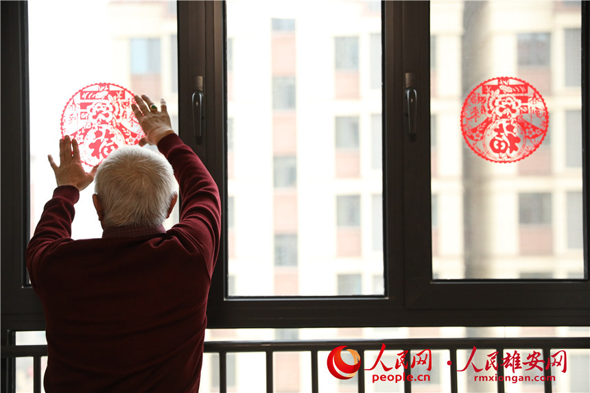 圖為回遷居民正在為新房貼上窗花。人民網 楊華龍攝