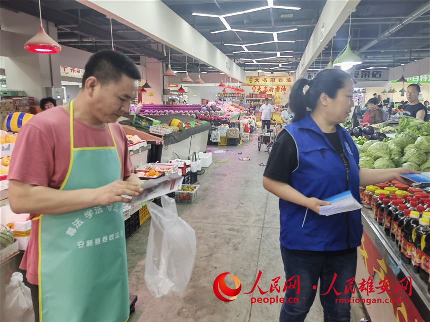 普法活動進市場。安新縣委政法委供圖