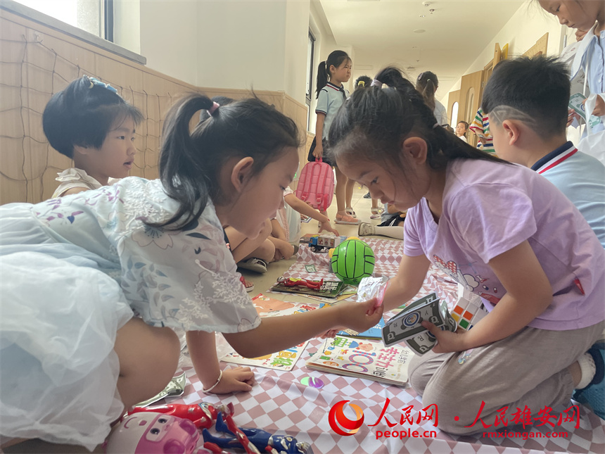 圖為“集市行樂”活動中，學(xué)生用“悅?cè)輲拧边M(jìn)行交易。雄安容和悅?cè)萦變簣@供圖